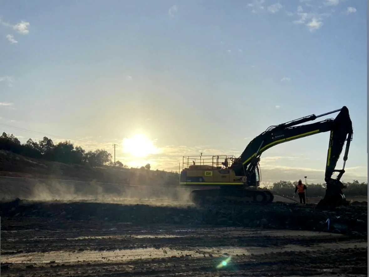 Excavator at first light on a bulk earthworks pad