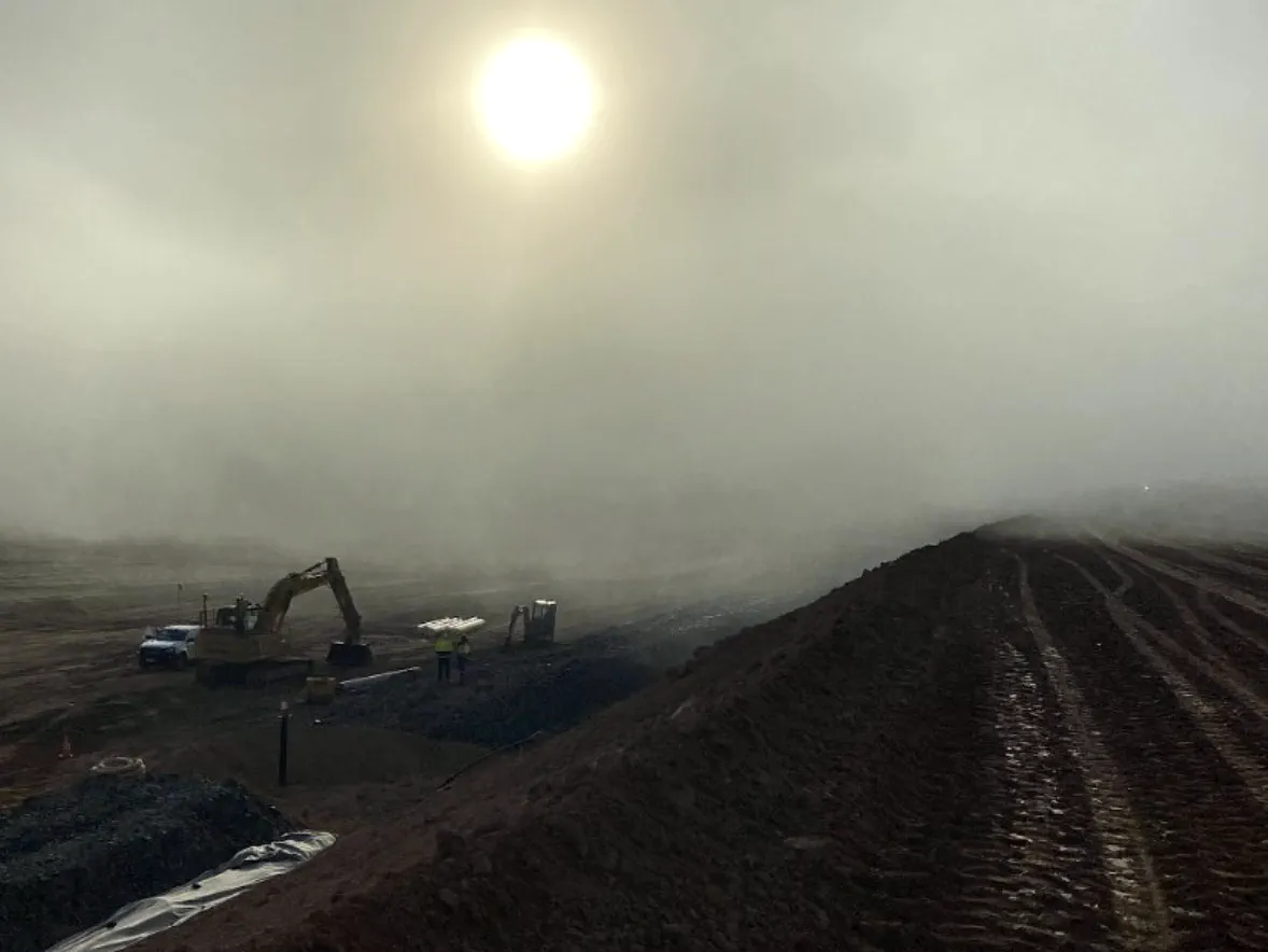 Drainage and pipe works in morning fog beside an embankment