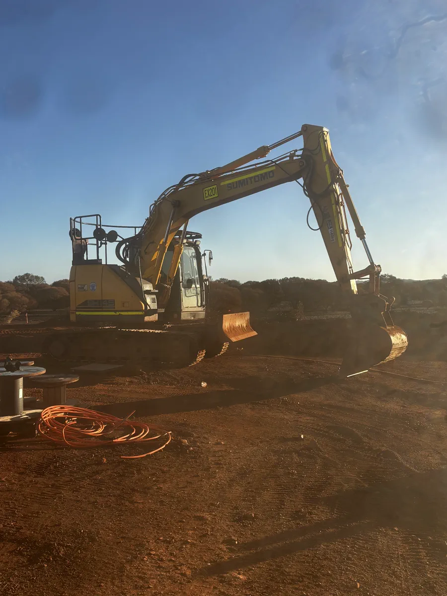 Excavator trenching for orange electrical conduit runs