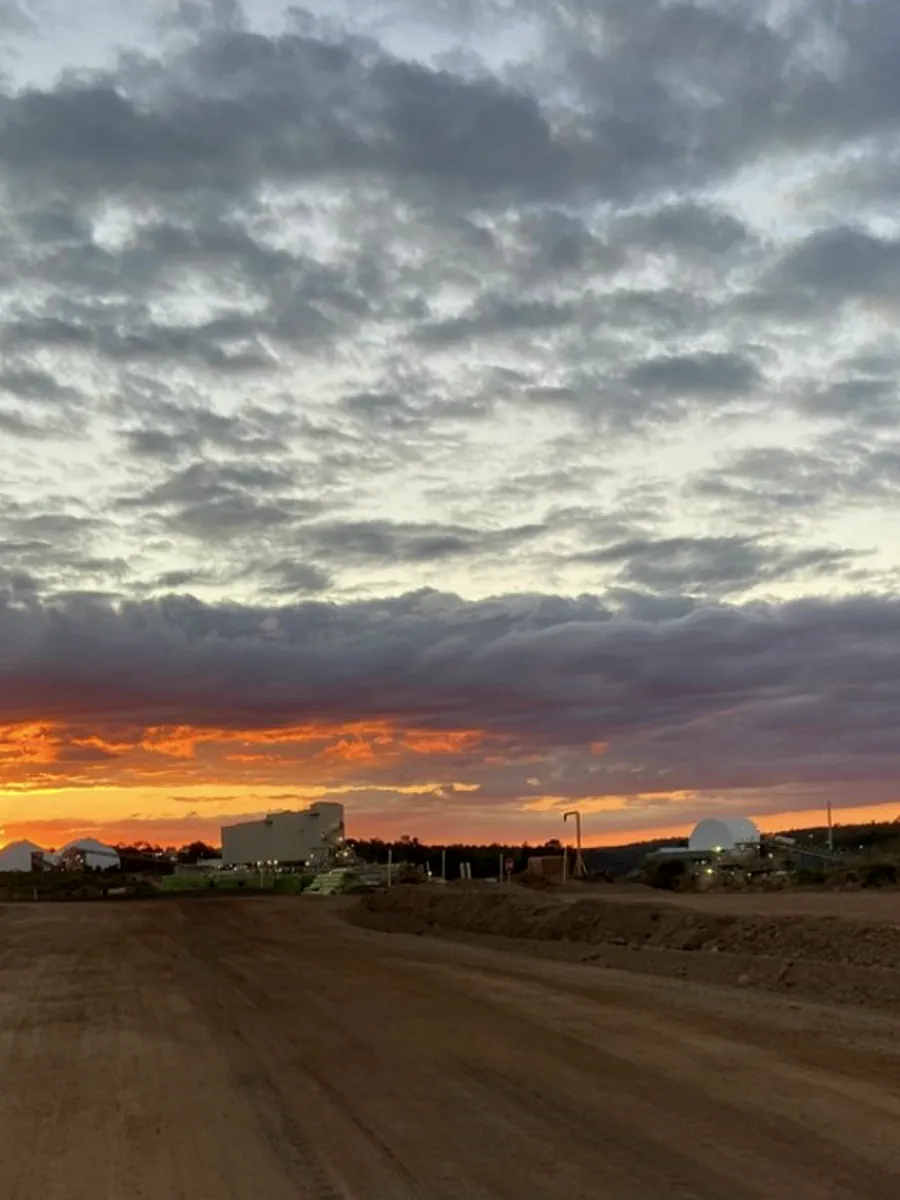 Sunset over a haul road with plant silhouetted on the horizon